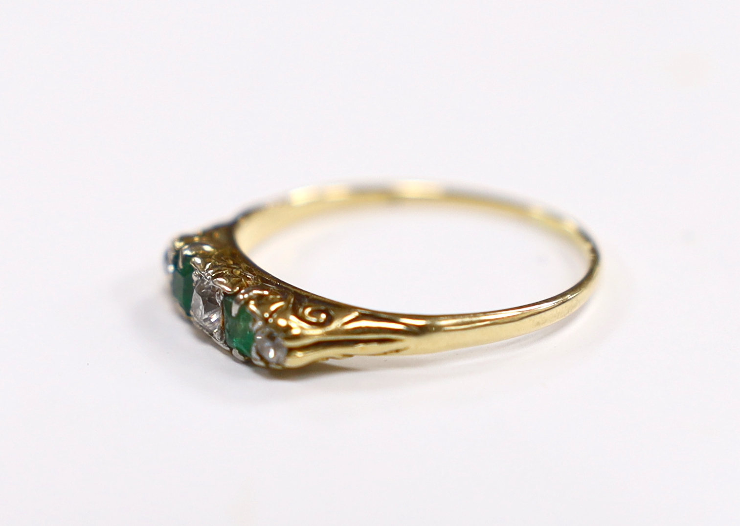 An 18ct, two stone emerald and three stone diamond set half hoop ring, size U, gross weight 2.8 grams, in a book shaped box.